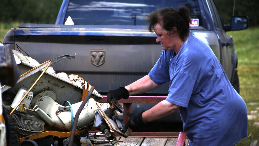 Woman organizes garbage on trailer.