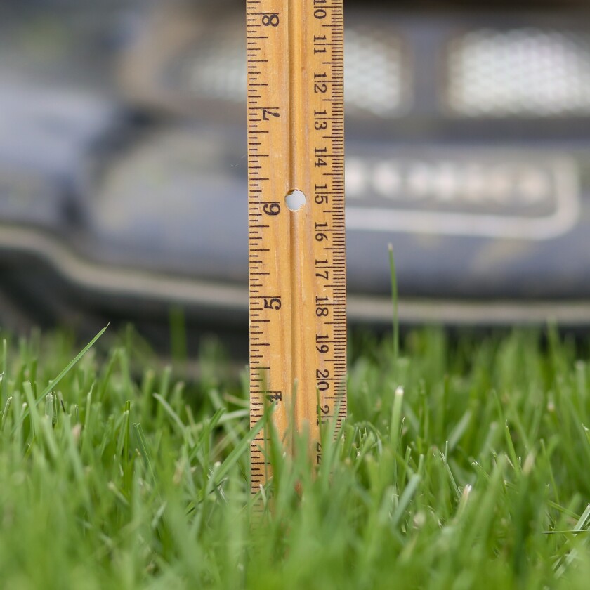 Doporučená výška sečení je mezi 3 a 4 palci. V pravítek je umístěn 12 palcový pravítko do trávy, která měří asi 4 palce vysoko. Sekačka na trávu je za tím zaměřena.