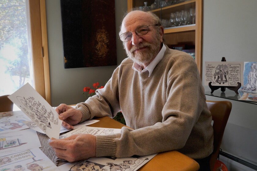 A smiling, bearded man holds a cartoon.