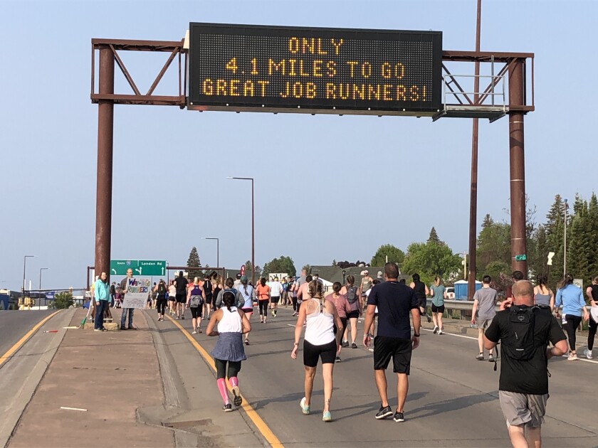 People walk and jog under digital sign that reads "Only 4.1 miles to go great job runners!"