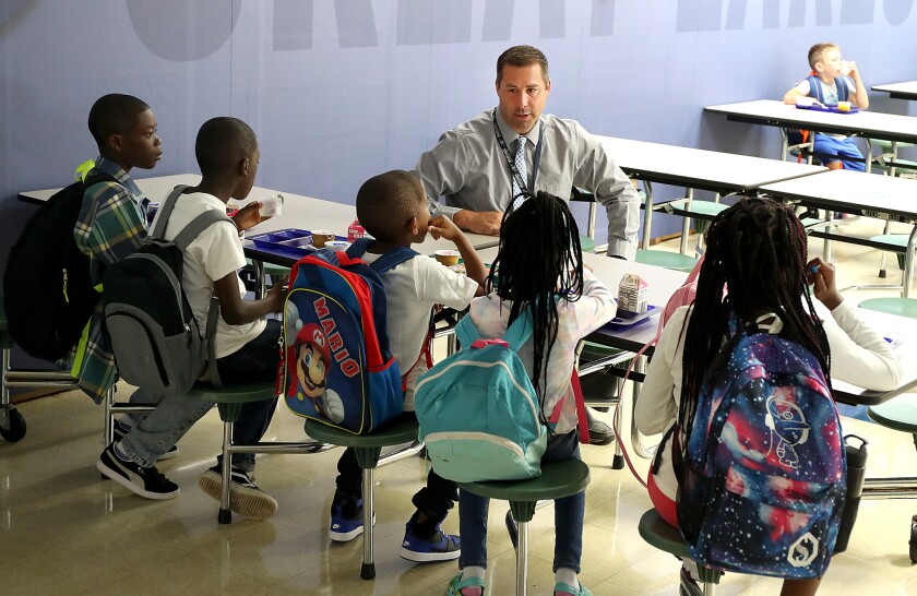 Great Lakes Elementary principal Ryan Haroldson talks with students as they eat breakfast