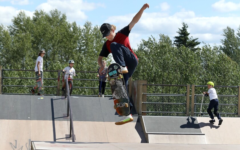 Graham Ward lands a trick off a jump as others watch at the Skate Park