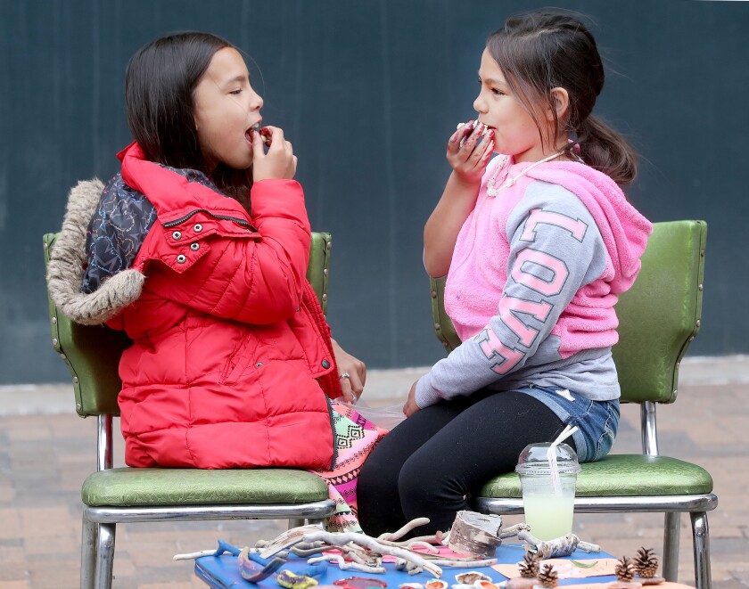 Beaulah Walker (left), 10, and her sister Hephzibah, 8, keep themselves entertained eating kettle corn, a favorite snack, during the first day of Sidewalk Days. Bob King / rking@duluthnews.com