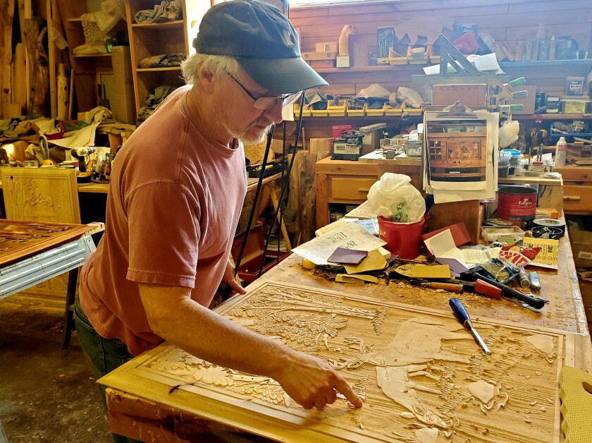 Man stands with wood carved door