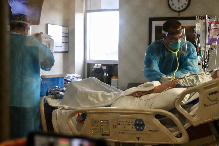Sanford Health registered respiratory therapist Logan Bailey and a registered nurse checking vitals of a COVID-19 patient on the COVID ward at the downtown Sanford hospital on Tuesday, Dec. 22.jpg