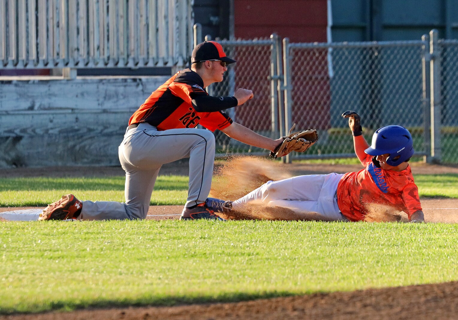 Third basemen fields the ball as another players slides into third.