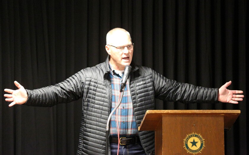 A man with his arms stretched out while speaking at a Veterans Day event.