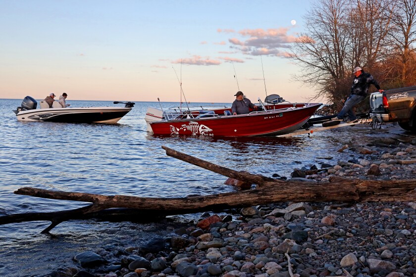 Anglers put their boats in the water at a boat landing on Mille Lacs at sunset.