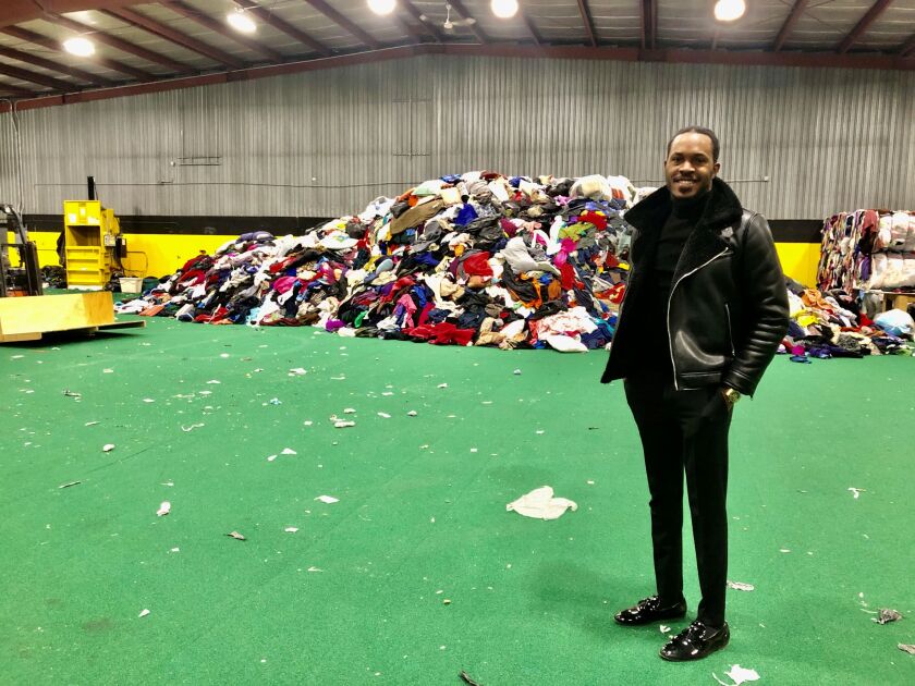 Rolland Elendu stands before a 14-foot-high "mountain" of textiles, which will eventually be baled and sold through Elendu Textiles, a textile-recycling business in north Fargo.