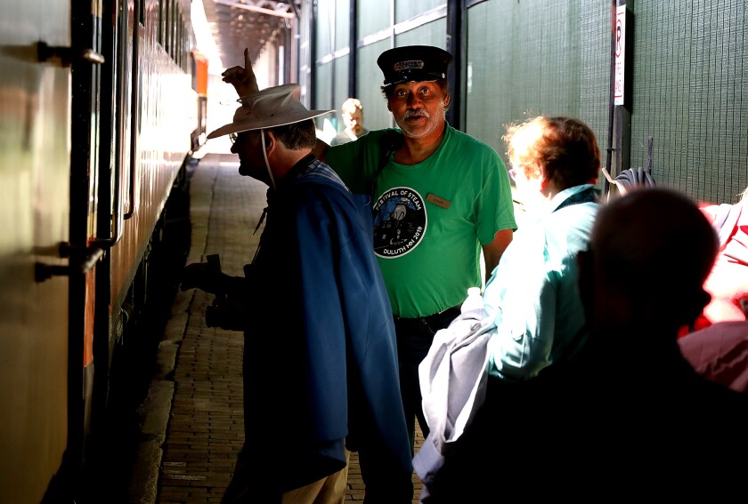 Porter Jerry McGee helps cruise ship passengers board the North Shore Scenic Railroad