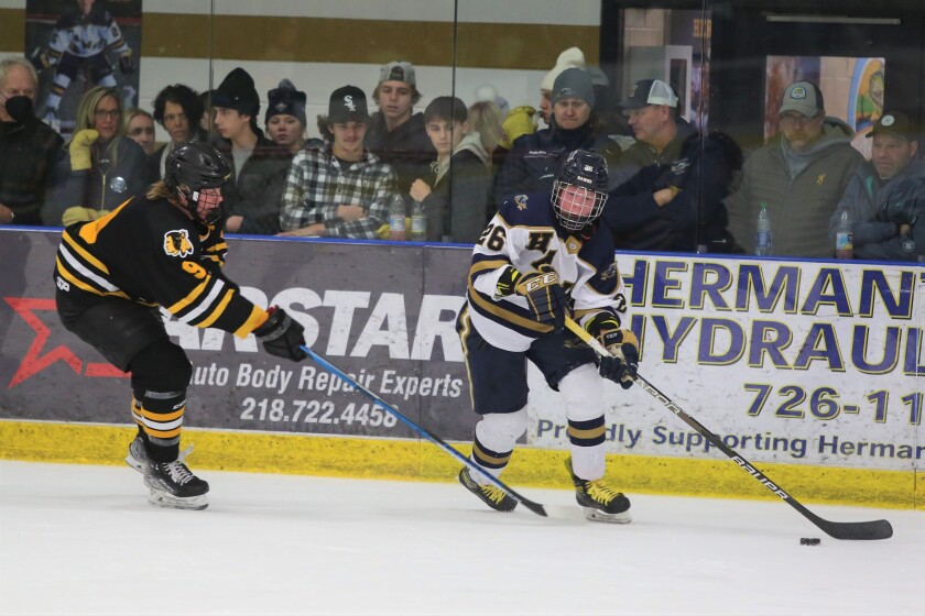 Hermantown's Max Plante looks for an open man while Warroad's Matt Hard tries to defend.