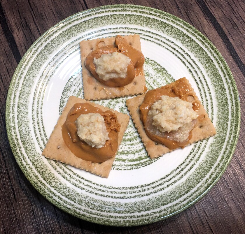 Three crackers topped with peanut butter and horseradish
