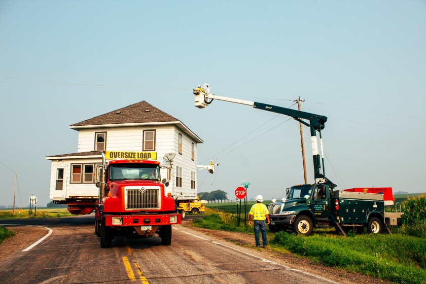 Workers with the Renville-Sibley Cooperative Power Association clear the way for a rural house moving.