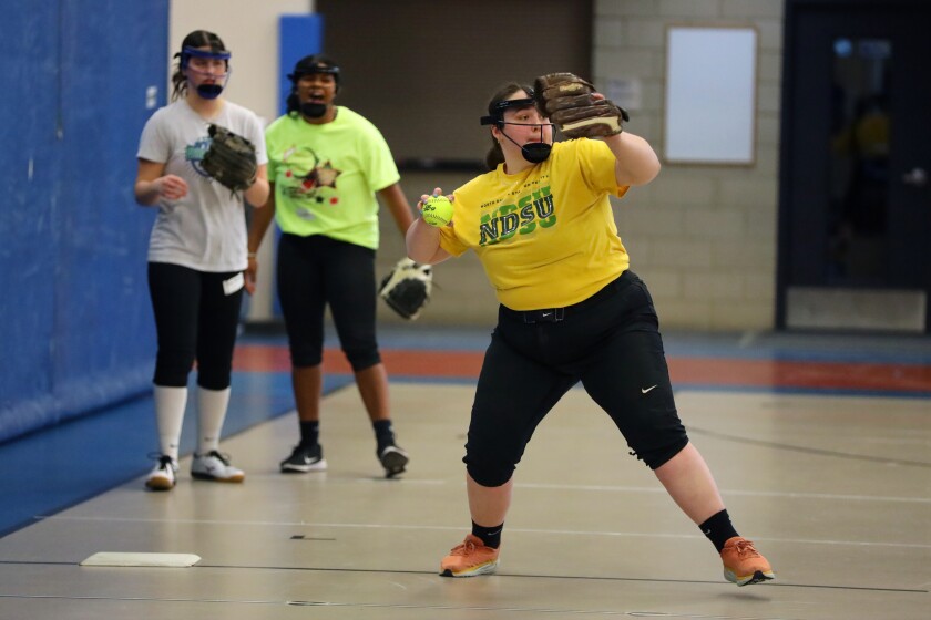 A softball player throws the ball during a drill.