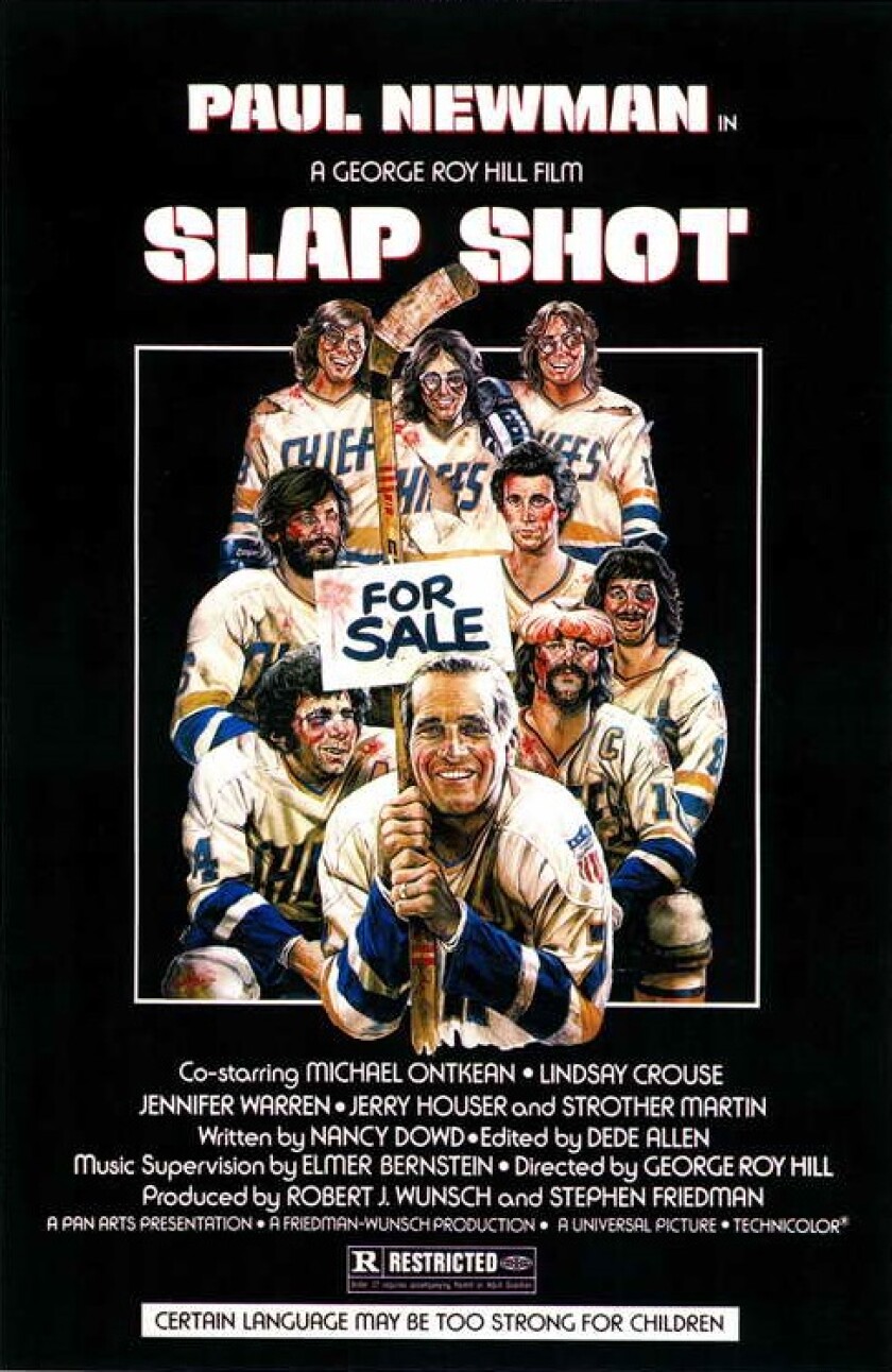 Movie poster for "Slap Shot," with a grinning Paul Newman holding a sign that reads FOR SALE in front of a team of bloody hockey players.