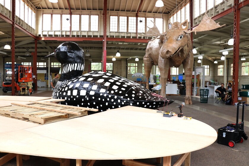 Giant loon sits next to a wooden platform currently under construction.