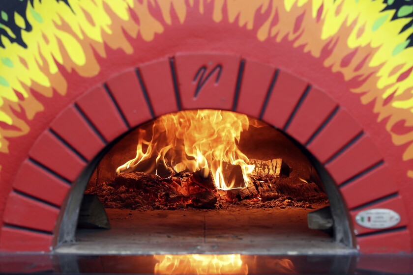 A wood fire burns in a pizza oven.