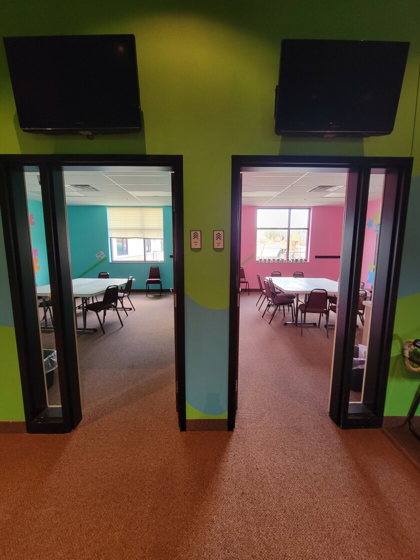 Two side-by-side classroom, one with blue walls and one with pink.