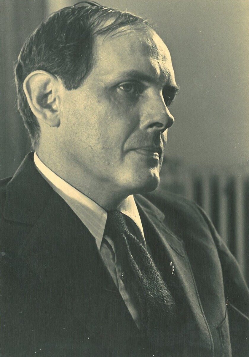 Photograph of a white man in a suit, looking pensive.