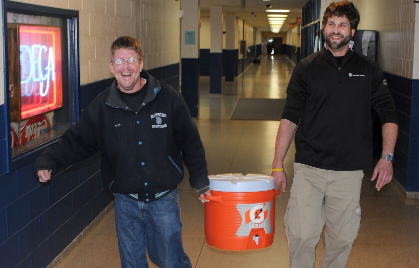 Superior trainer Mike Gogolin, right, carries a water jug with Spartan super fan Josh Noble
