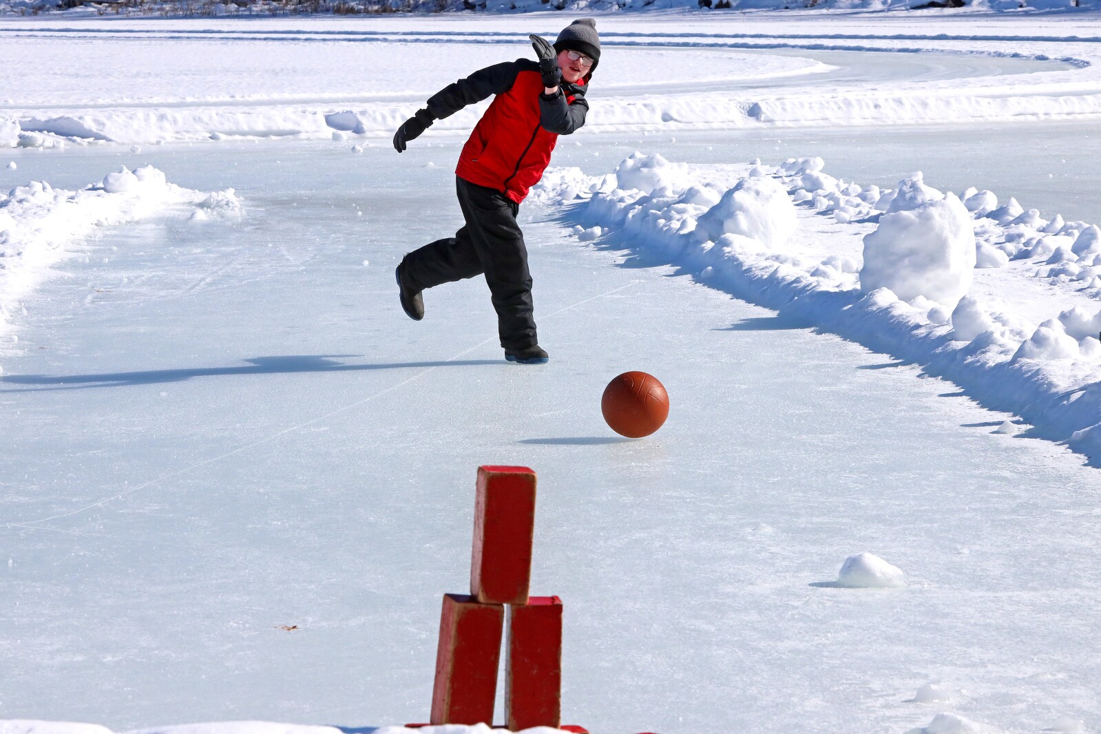 Brady Meyer throws the ball while ice bowling. Blocks are in the foreground.