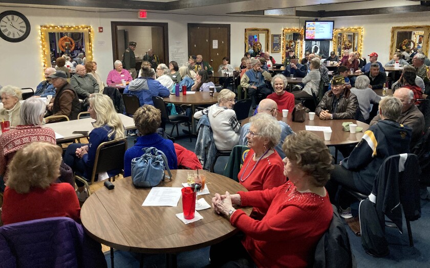 People sitting at tables and socializing at a Veterans Day event.