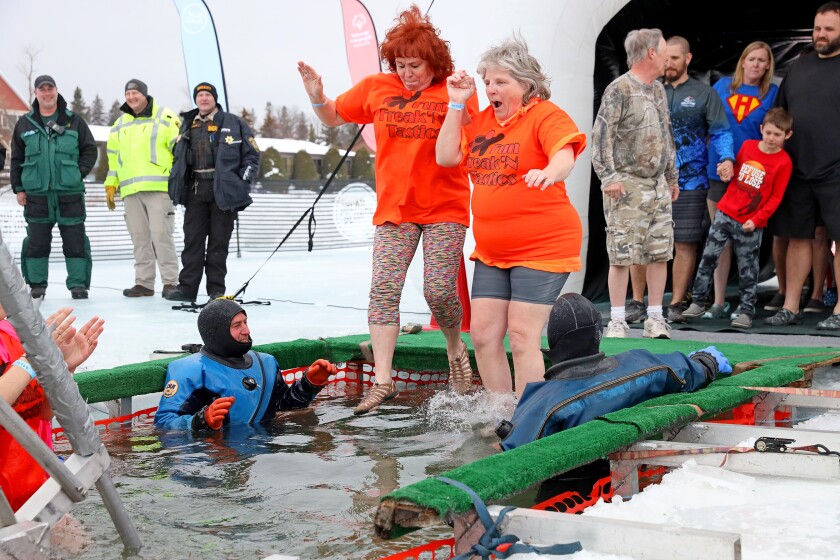 People jump into the water during the Polar Plunge event on Pelican Lake.