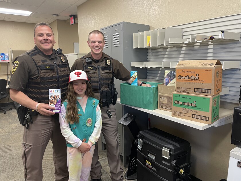 Girl Scout Ellisyn Ahmann, 11, shares some smiles and sweets with two North Dakota Highway Patrol officers during a law enforcement meeting Tuesday, June 28, 2022, in Dickinson. 