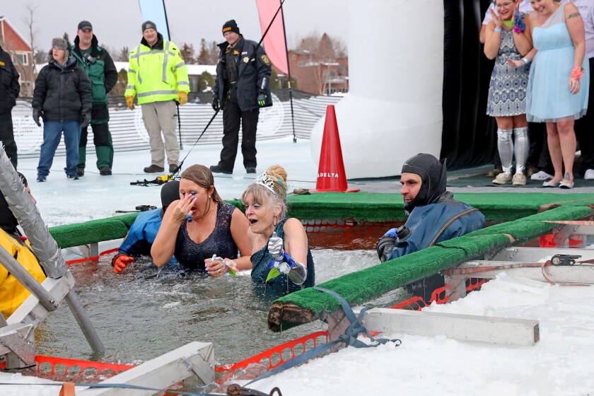 People jump into the water during the Polar Plunge event on Pelican Lake.