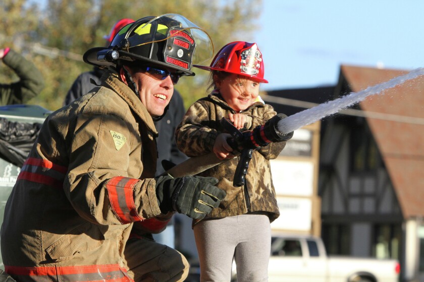 Fire fighter Brian Kargel helps Kendall Fleischhacker direct a spray of water from a fire hose Thursday during the Brainerd Fire Department’s open house. (Kelly Humphrey, Brainerd Dispatch)