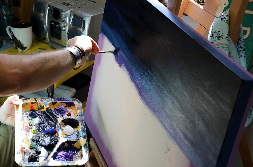 Ojibwe artist Sam Zimmerman uses a fan brush to mix purple paint in with the wet deep blue tones on the canvas