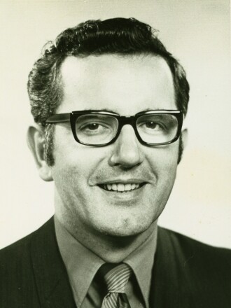 Portrait of white man in his early 40s, wearing glasses and smiling in business suit.