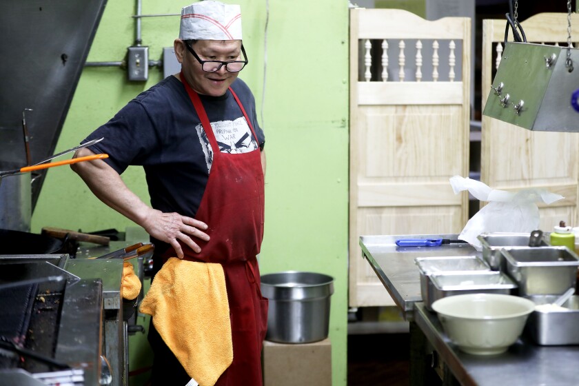 A man smiling while working in a kitchen.