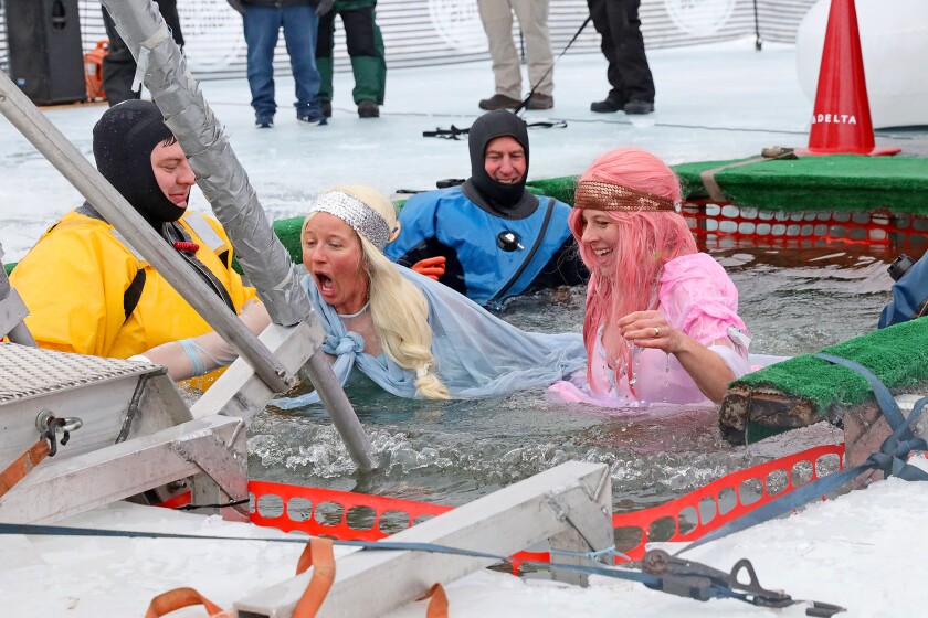People jump into the water during the Polar Plunge event on Pelican Lake.