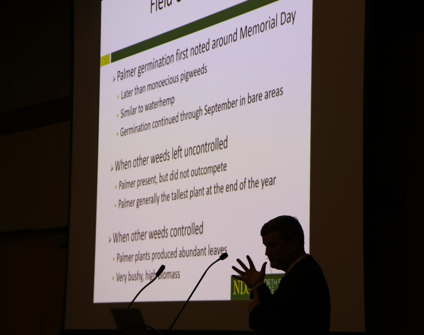 North Dakota State University weed researcher Quincy Law stands in silhouette in front of a slide about Palmer amaranth research at Wild World of Weeds, a seminar in Fargo on Jan. 18, 2022.