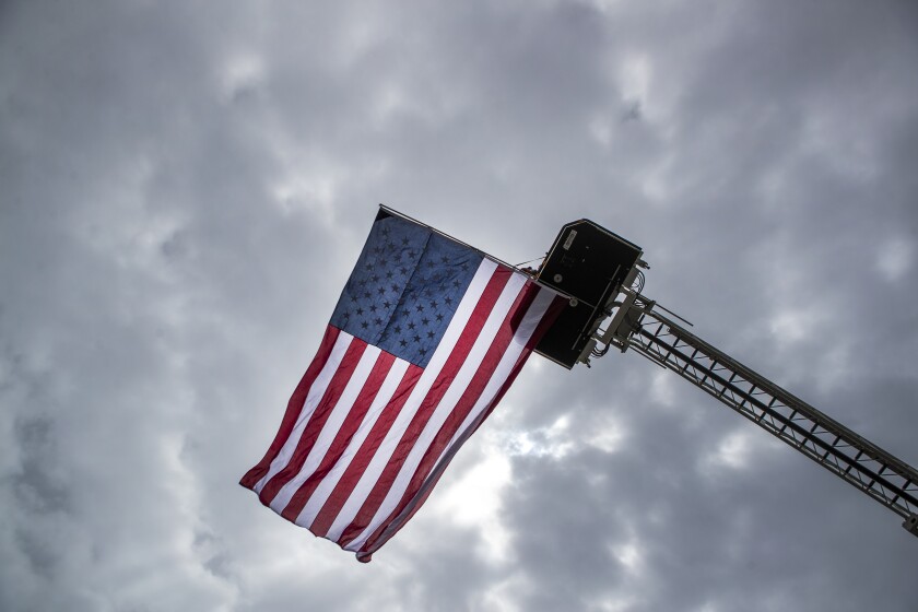 An American flag flies from a fire engine ladder outside Refuge Church during the funeral for Blomkest Fire Department firefighter Ryan Leif Erickson on Friday, May 20, 2022.