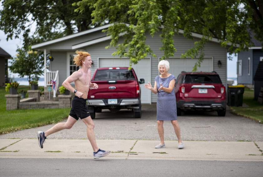 Runner Riley Hanson is cheered on by Green Lake resident Carol Maursetter as Hanson runs along North Shore Drive during the Green Lake Road Race in Spicer on the morning of Sunday, June 3, 2022.