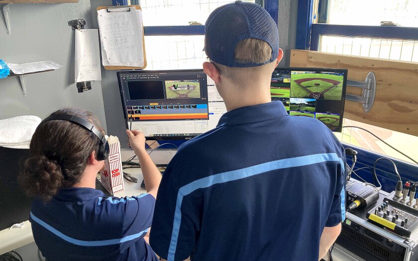 Two member of the Duluth Huskies graphics team watching monitors