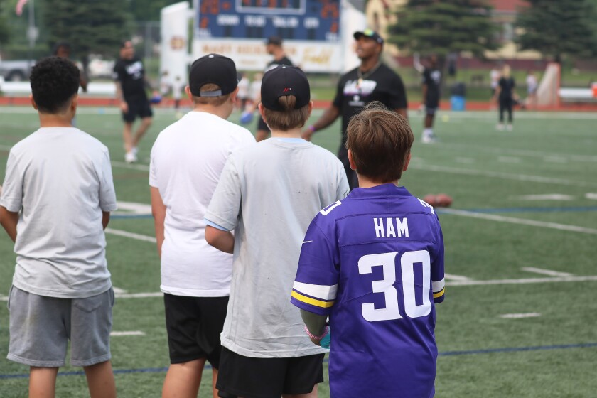 A young boy wearing the jersey of a pro football player at that player's youth camp.