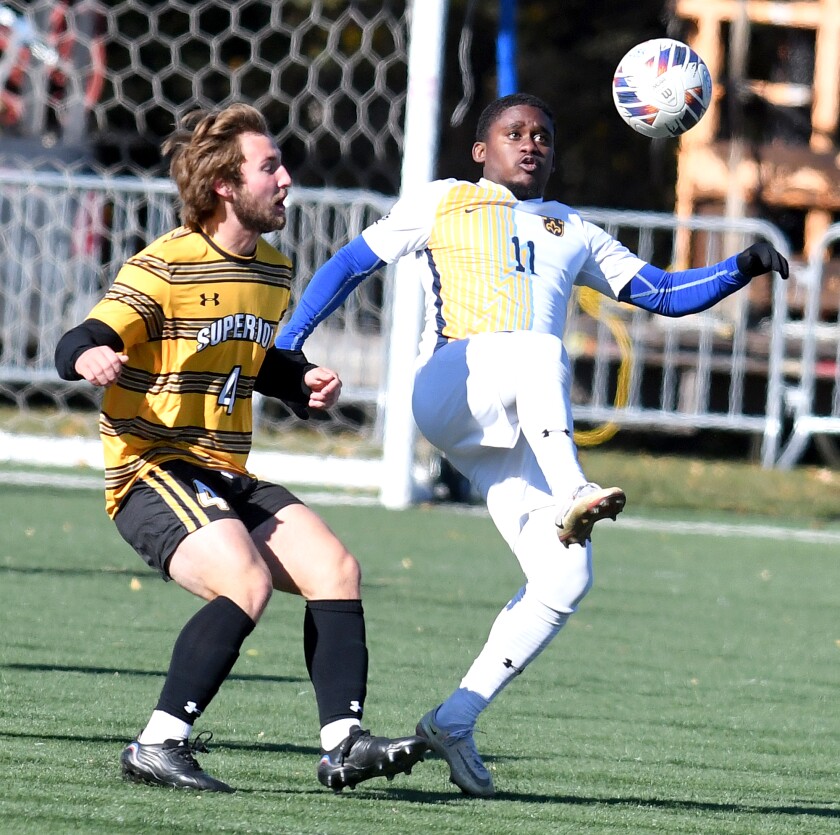 El jugador de St. Scholastica Achim Robotham (11), de Kingston, Jamaica, lanza el balón sobre Andy Rowland del UW-Superior (4) 