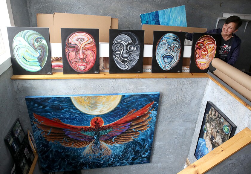 Woman looks at series of five mask paintings.