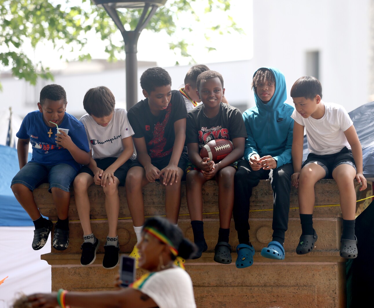Kids sit atop the old courthouse stone watching the crowd during the International Festival Saturday, July 9, 2022.