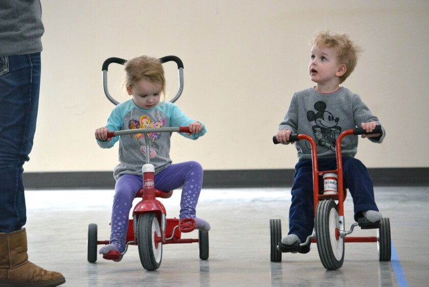 Three-year-old twin siblings Jenna and Blaine Foss try out a couple of tricycles Friday during the Movement And Play program at the armory. (Jordan Shearer | Bemidji Pioneer)