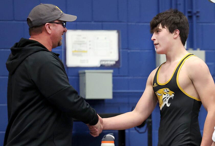 Coach congratulates wrestler.