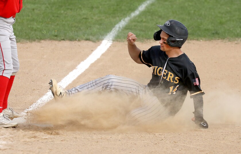 Northwestern’s Kole Paulson (14) kicks up dirt as he slides safely into third base