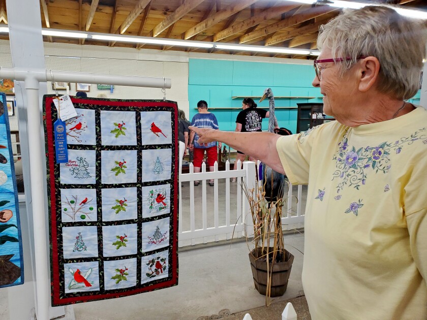 Woman points at quilt with cardinals on it