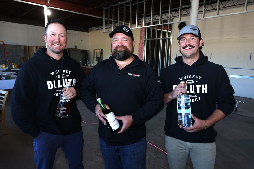 Men hold cocktail bottles inside building under construction
