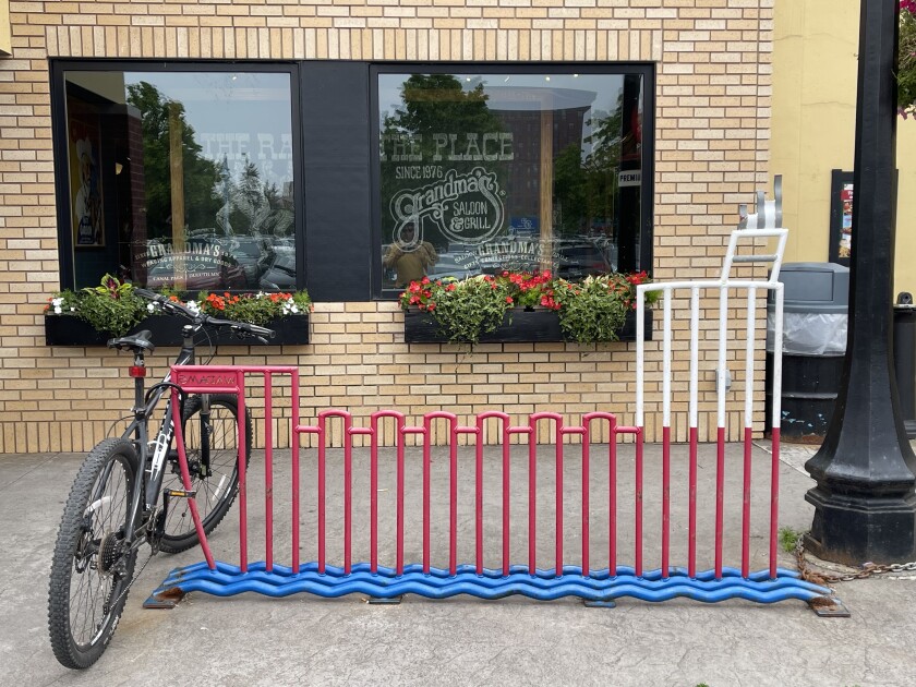 A bike rack in the shape of a lake-going cargo ship has a single bike locked to the far end, with slats too narrow to accommodate tires of other bikes.