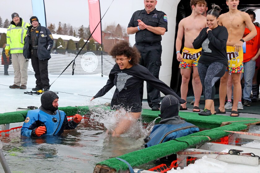 People jump into the water during the Polar Plunge event on Pelican Lake.