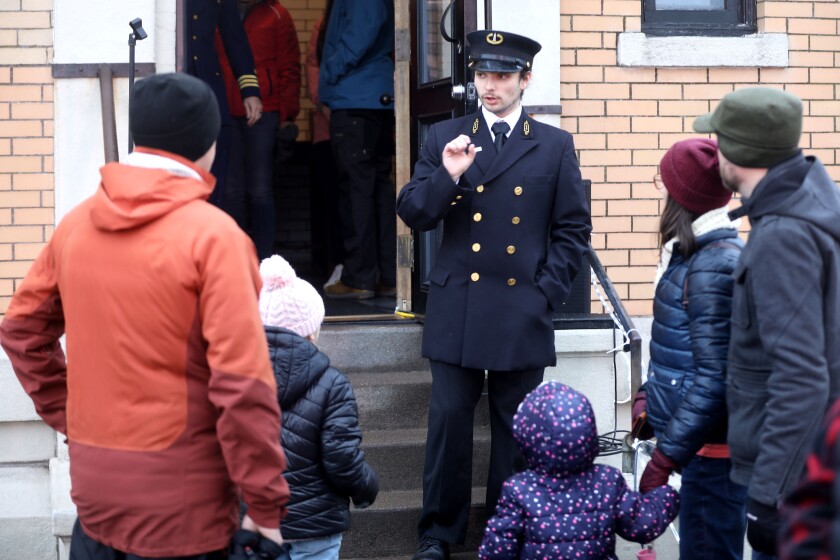 A man in uniform assisting guests at a lighthouse.
